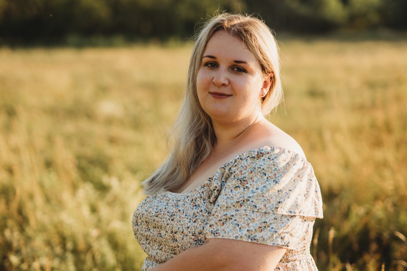 Eine Frau mit blonden Haaren in einem blumigen Kleid läuft über ein Feld.